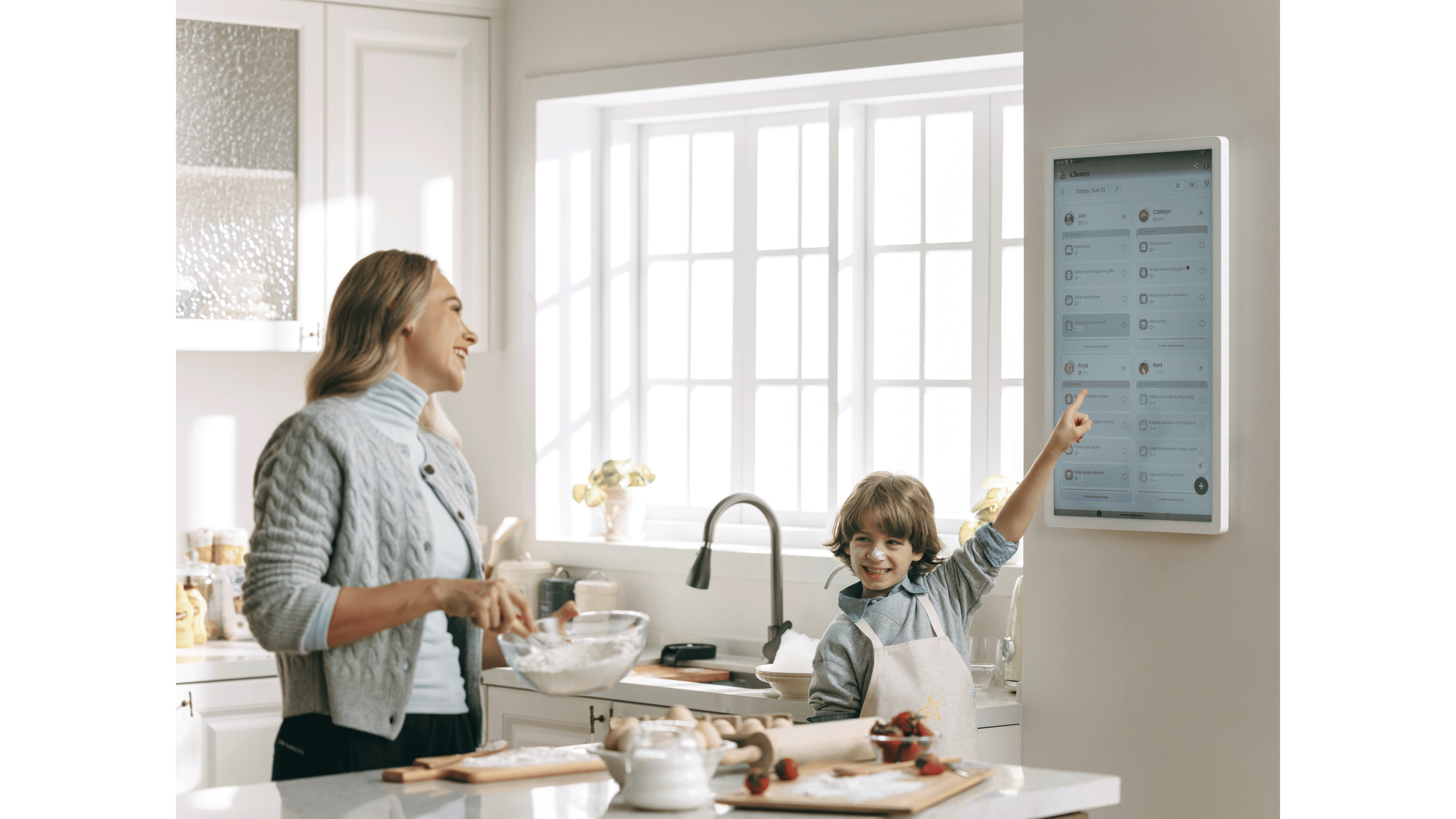 Boy pointing at Chores interface on a Cozyla digital calendar while cooking with mom