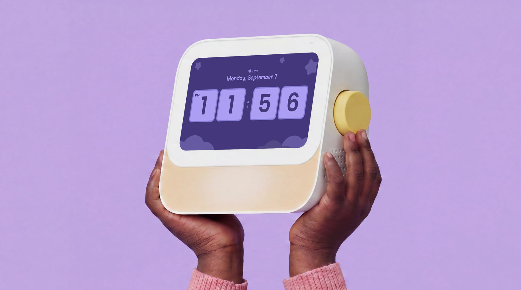 A person holds a Cozyla digital alarm clock with a cream and white body, a purple display screen showing the time 11:56, and a yellow side button against a solid lavender background.